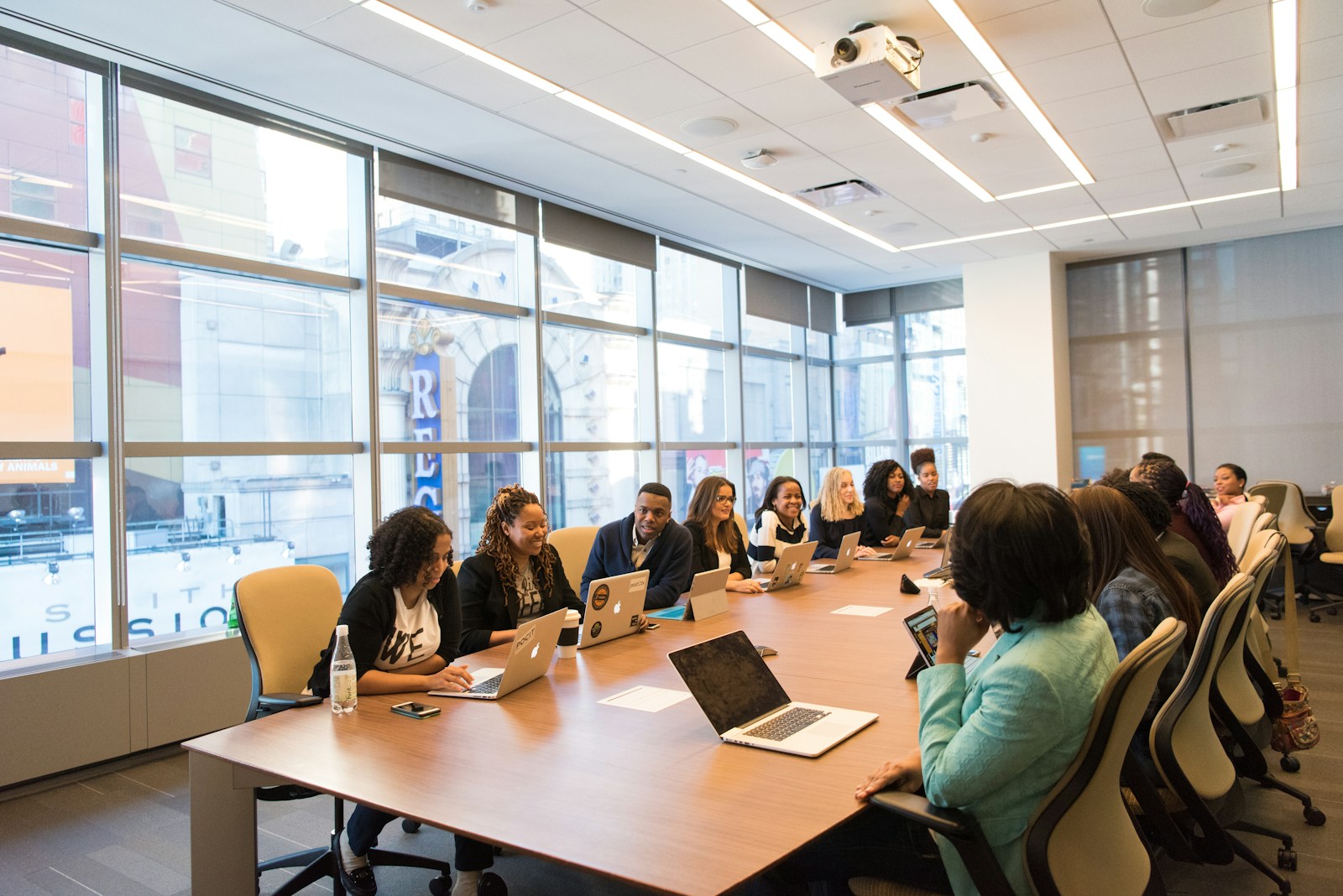 group of people sitting beside rectangular wooden table with laptops, business